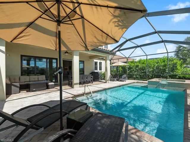 View of swimming pool featuring a patio, a pool with connected hot tub, outdoor lounge area, glass enclosure, and ceiling fan