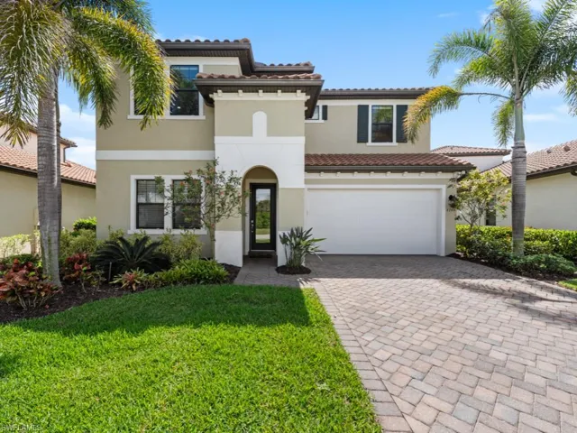 Mediterranean / spanish home featuring an attached garage, a tiled roof, decorative driveway, stucco siding, and a front lawn