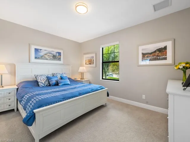 Bedroom with baseboards, visible vents, and light colored carpet