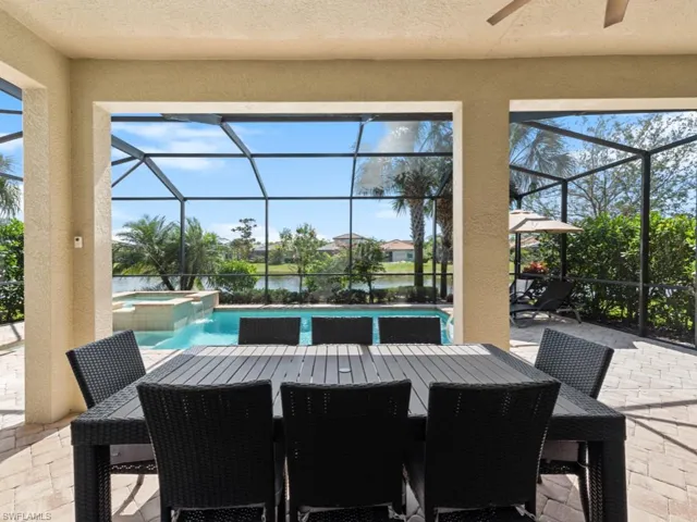 View of patio / terrace with a lanai, a pool with connected hot tub, and outdoor dining area