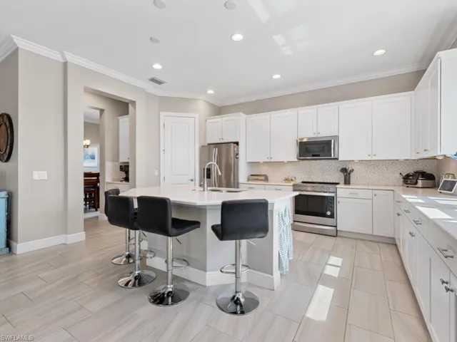 Kitchen with an island with sink, appliances with stainless steel finishes, decorative backsplash, and a sink