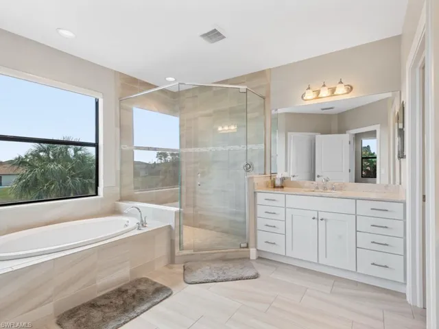 Bathroom featuring a stall shower, visible vents, vanity, and a bath