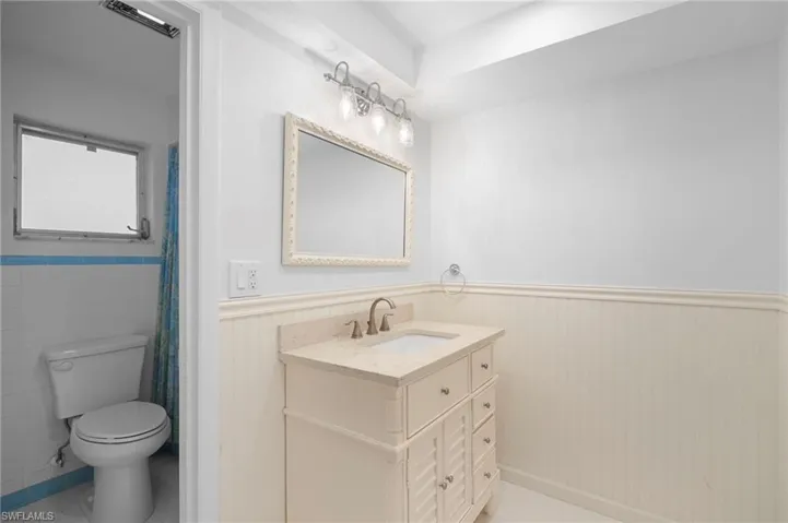 Full bathroom with wainscoting, vanity, and a shower with curtain