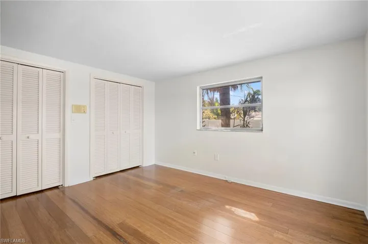 Unfurnished bedroom with two closets and hardwood / wood-style floors