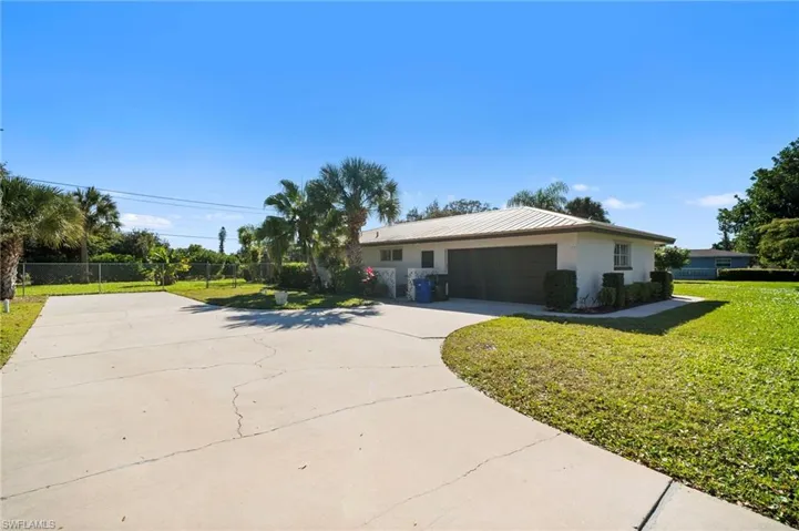 Ranch-style house with stucco siding, driveway, a garage, and a metal roof