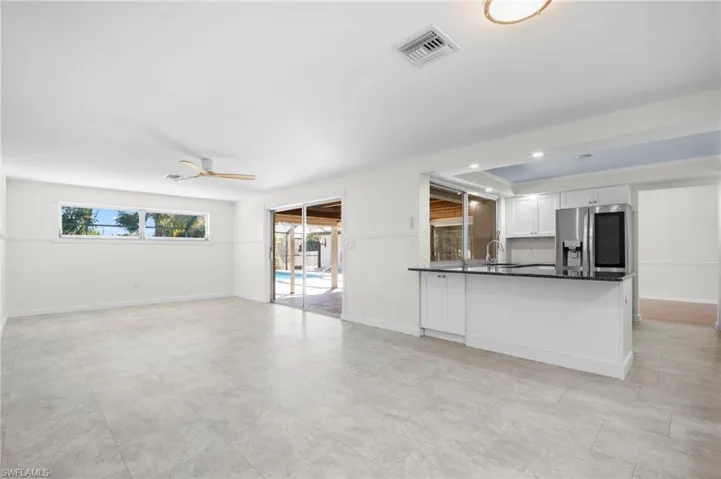 Unfurnished living room featuring a tray ceiling, recessed lighting, and a ceiling fan