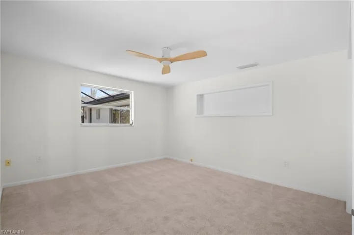 Unfurnished room featuring light carpet and a ceiling fan