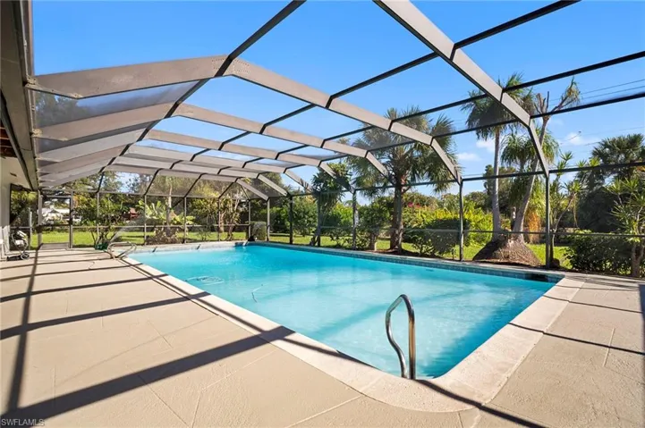 Swimming pool featuring glass enclosure, a patio, and a sunroom