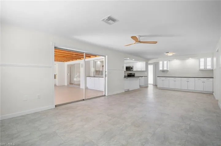 Unfurnished living room featuring baseboards and ceiling fan