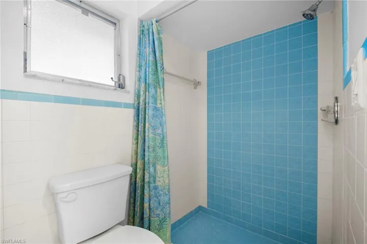 Full bathroom featuring a stall shower and tile walls
