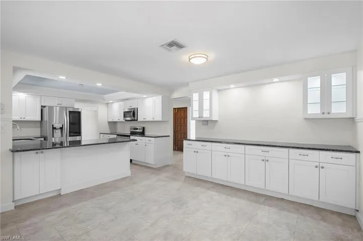 Kitchen with white cabinets, appliances with stainless steel finishes, recessed lighting, a peninsula, and dark stone countertops