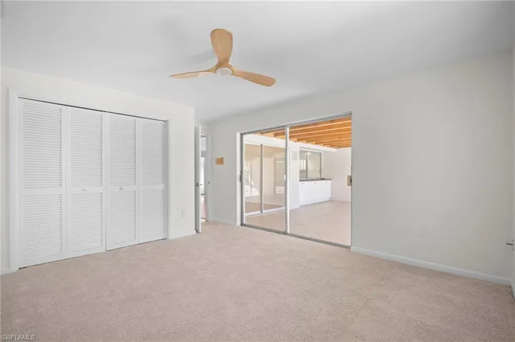 Unfurnished bedroom featuring a closet, light carpet, ceiling fan, and access to exterior