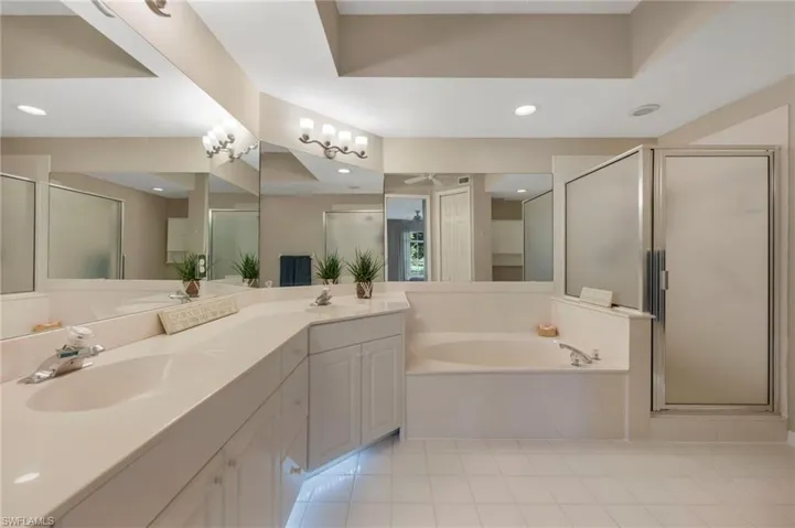 Bathroom with double sink vanity, tile floors, and plus walk in shower