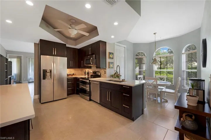 Kitchen featuring hanging light fixtures, appliances with stainless steel finishes, tasteful backsplash, light tile flooring, and ceiling fan