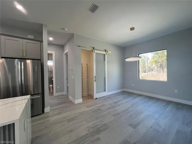 Unfurnished dining area featuring a barn door and light wood-style flooring