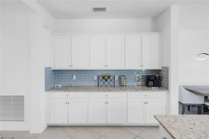 Kitchen featuring white cabinetry, light stone countertops, and tasteful backsplash