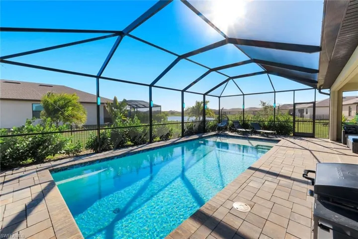 Outdoor pool with grilling area, a sunroom, a patio area, and a lanai