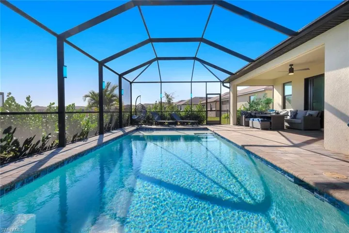 Outdoor pool with a sunroom, an outdoor hangout area, a patio, and glass enclosure