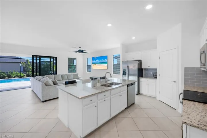 Kitchen featuring white cabinets, light stone countertops, a ceiling fan, light tile patterned flooring, and recessed lighting