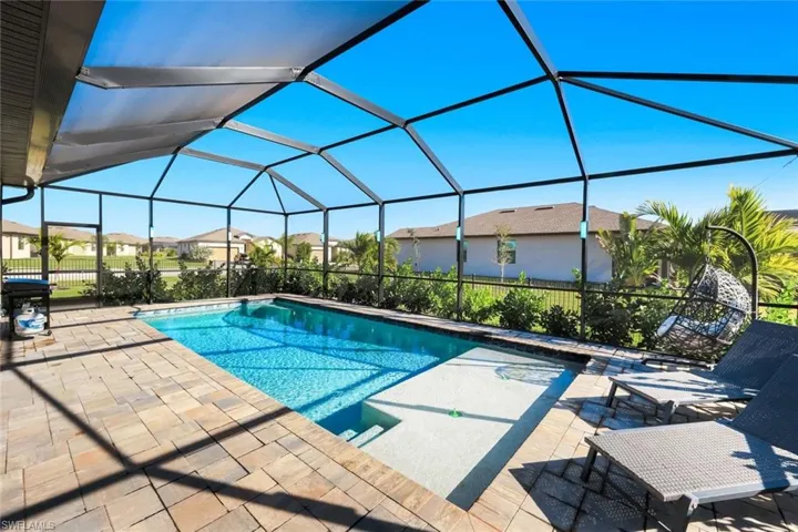 Swimming pool with a sunroom, a lanai, a residential view, and a patio