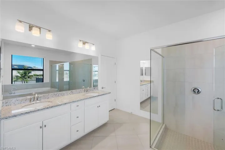 Full bathroom with double vanity, a stall shower, a garden tub, and light tile patterned flooring