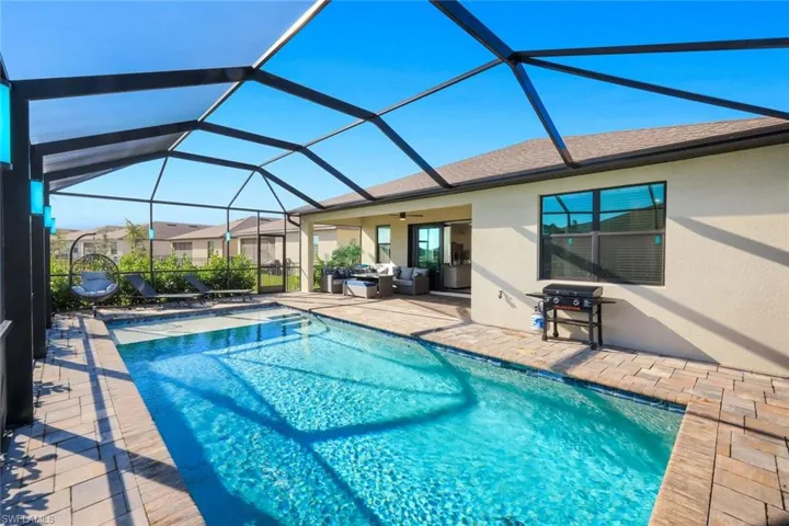 Swimming pool featuring a patio area, a sunroom, a lanai, outdoor seating, and a grill
