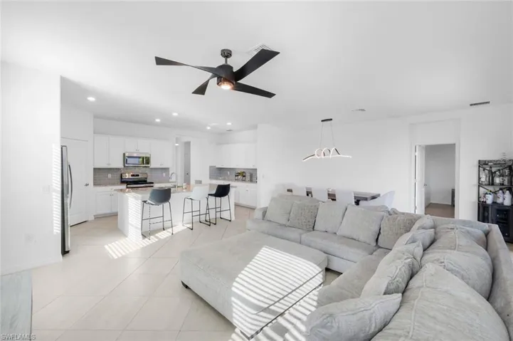 Living area featuring ceiling fan, light tile patterned flooring, and recessed lighting