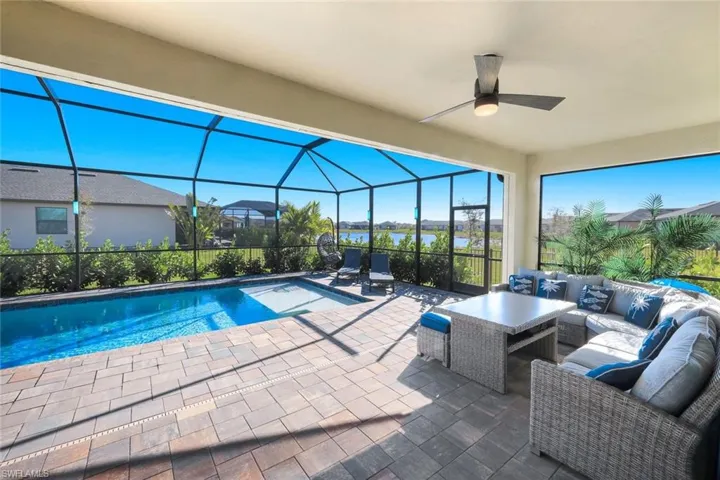 Swimming pool with outdoor furniture, a sunroom, a lanai, a patio, and a water view