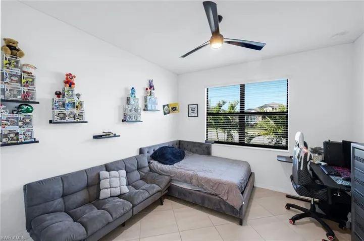 Tiled bedroom featuring a desk and ceiling fan