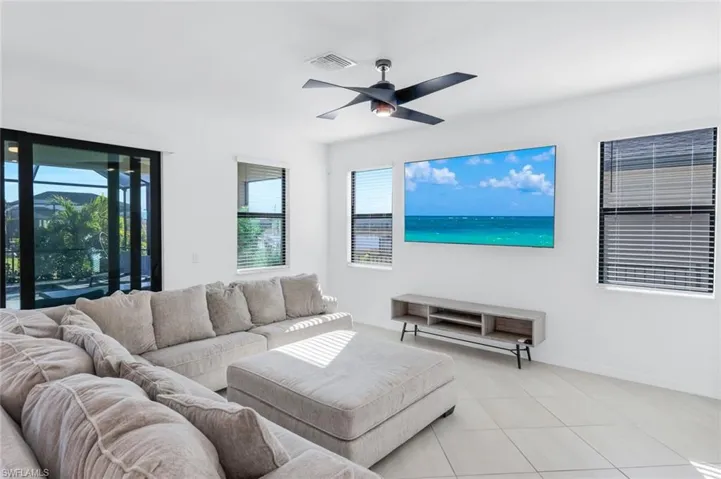 Tiled living room with a ceiling fan and baseboards