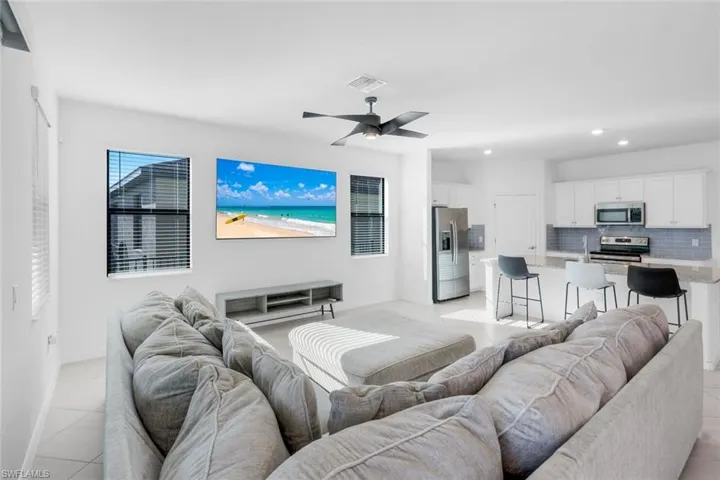 Living area with light tile patterned flooring, ceiling fan, and recessed lighting