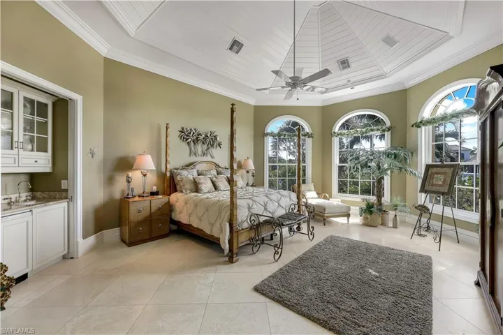The primary bedroom overlooking the Imperial River, complete with en suite bathroom and a wet bar. Notice the  tall southern facing windows and the ceiling treatment.