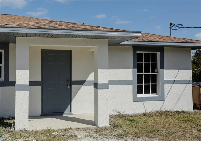 The property features a front entrance with a covered porch, a paneled entry door, and an exterior window with grilles