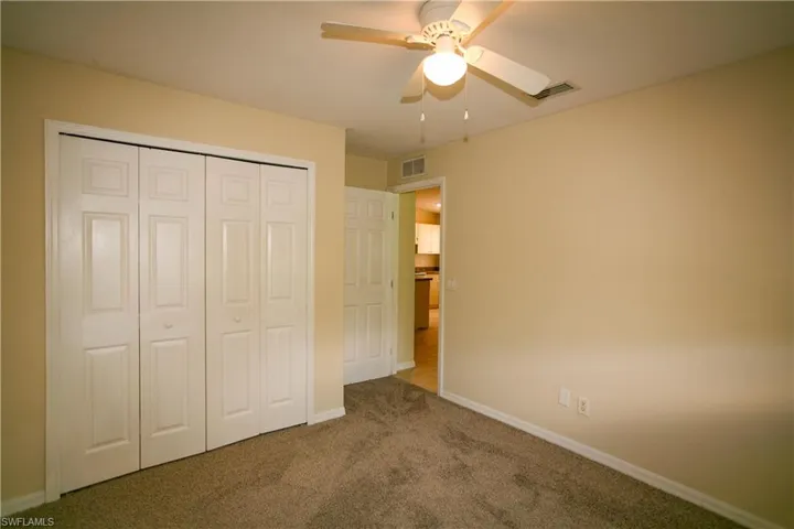 This room features wall-to-wall carpeting, a ceiling fan with lighting, and a closet with bifold doors