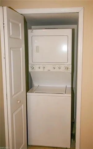 Dedicated laundry area featuring a white stacked washer and dryer unit, set within a bi-fold closet