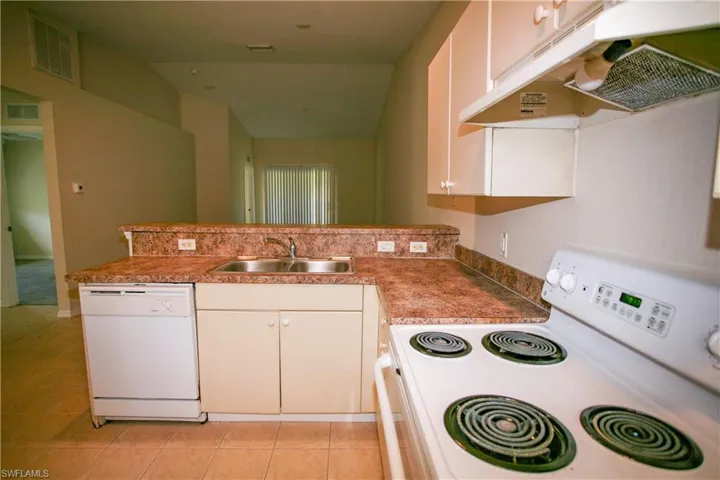 The kitchen features a double basin stainless steel sink, a white dishwasher, and a white electric range