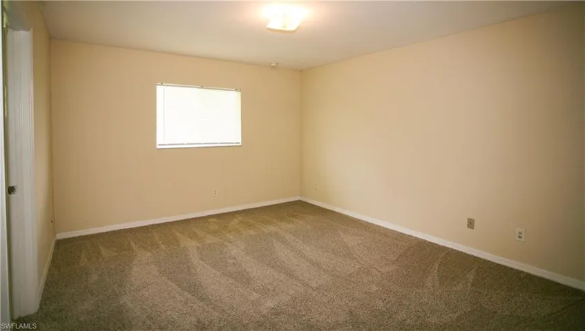 The room features neutral-toned walls, a window with blinds, and carpeted flooring