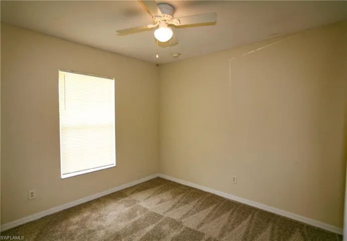 Room featuring light-colored walls, carpeted flooring, a window with blinds, and a ceiling fan with integrated lighting