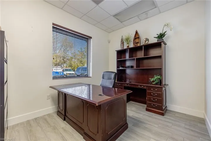 Office space with light wood-style floors, visible vents, a paneled ceiling, and baseboards