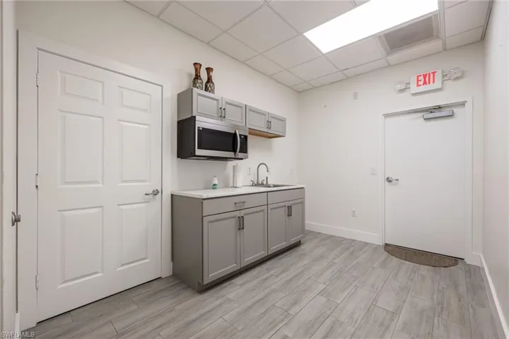 Private office area with light wood finished floors, a drop ceiling, and baseboards