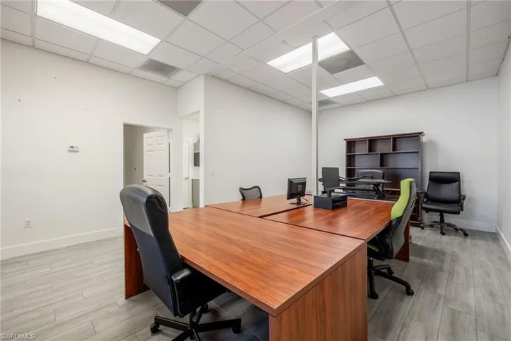 Office area featuring a drop ceiling, light wood-type flooring, and baseboards