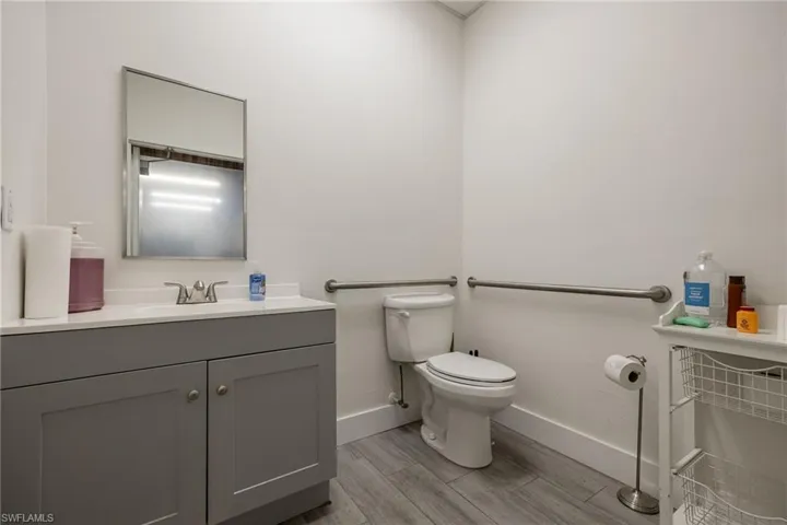 Half bath featuring vanity, toilet, wood finished floors, and baseboards