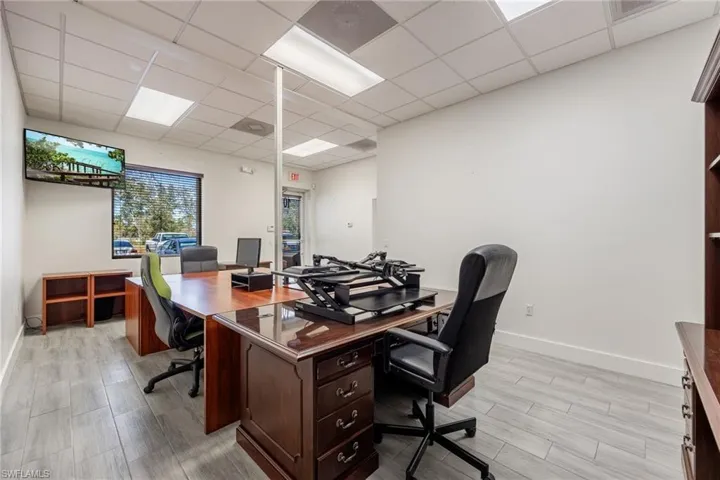 Office space featuring a drop ceiling, light wood-type flooring, and baseboards