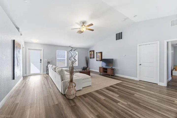 Living room featuring ceiling fan, vaulted ceiling, and wood finished floors