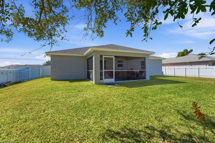 Back of house featuring a sunroom, a fenced backyard, stucco siding, and a shingled roof