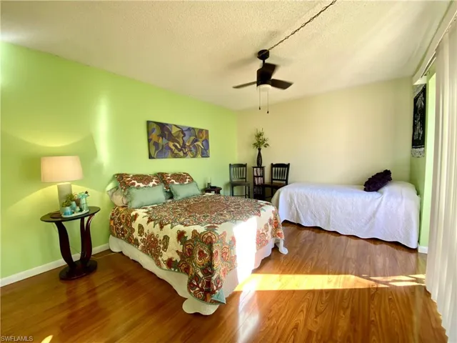 Bedroom with hardwood / wood-style flooring, ceiling fan, and a textured ceiling