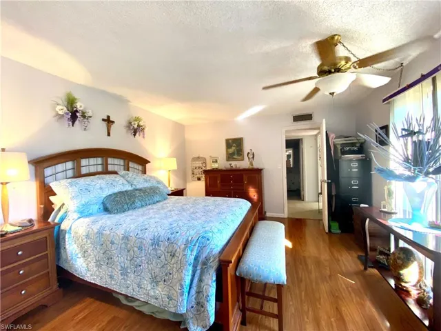 Bedroom with ceiling fan, wood-type flooring, and a textured ceiling