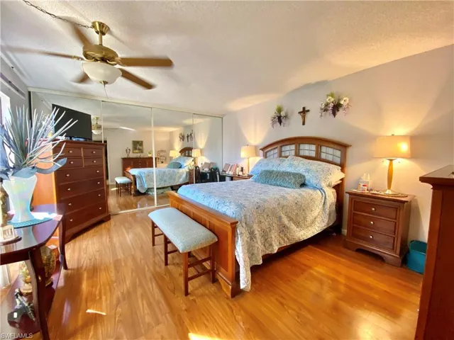 Bedroom with ceiling fan, light hardwood / wood-style flooring, and a textured ceiling