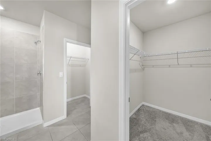 Spacious closet featuring light tile patterned flooring and light colored carpet