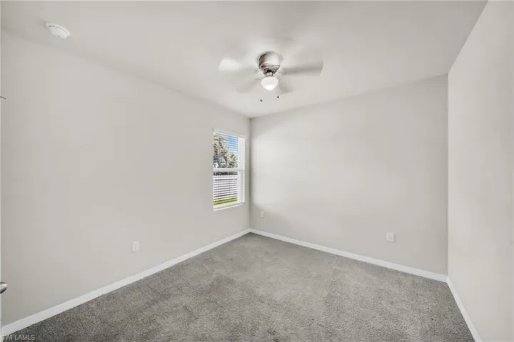 Carpeted spare room featuring baseboards and ceiling fan